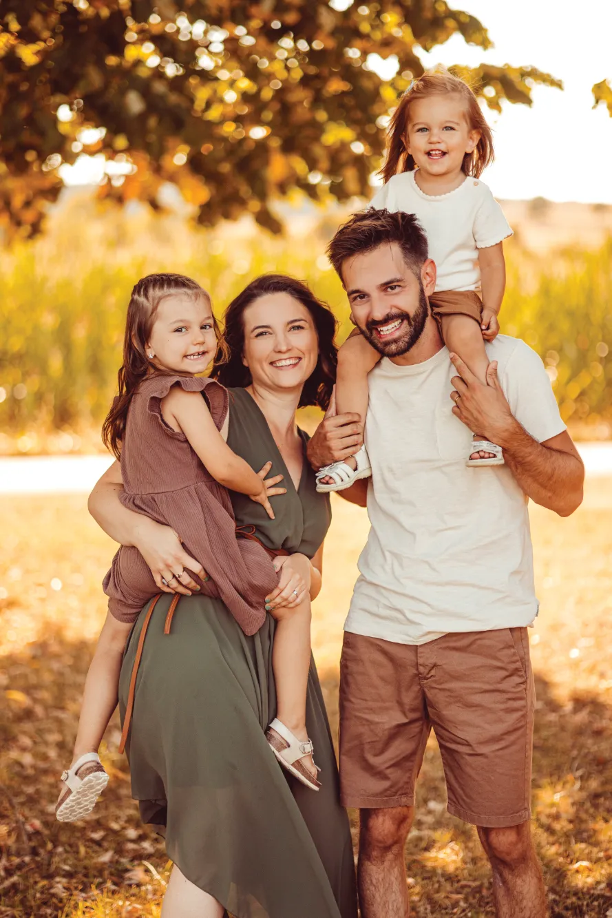 Schön bekleidete Kleinfamilie mit Kind auf dem Rücken des Vaters