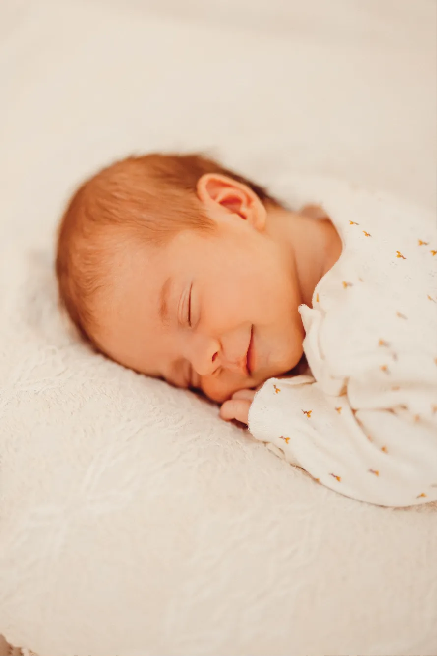 Hell bekleidetes Baby schlafend auf weicher Decke