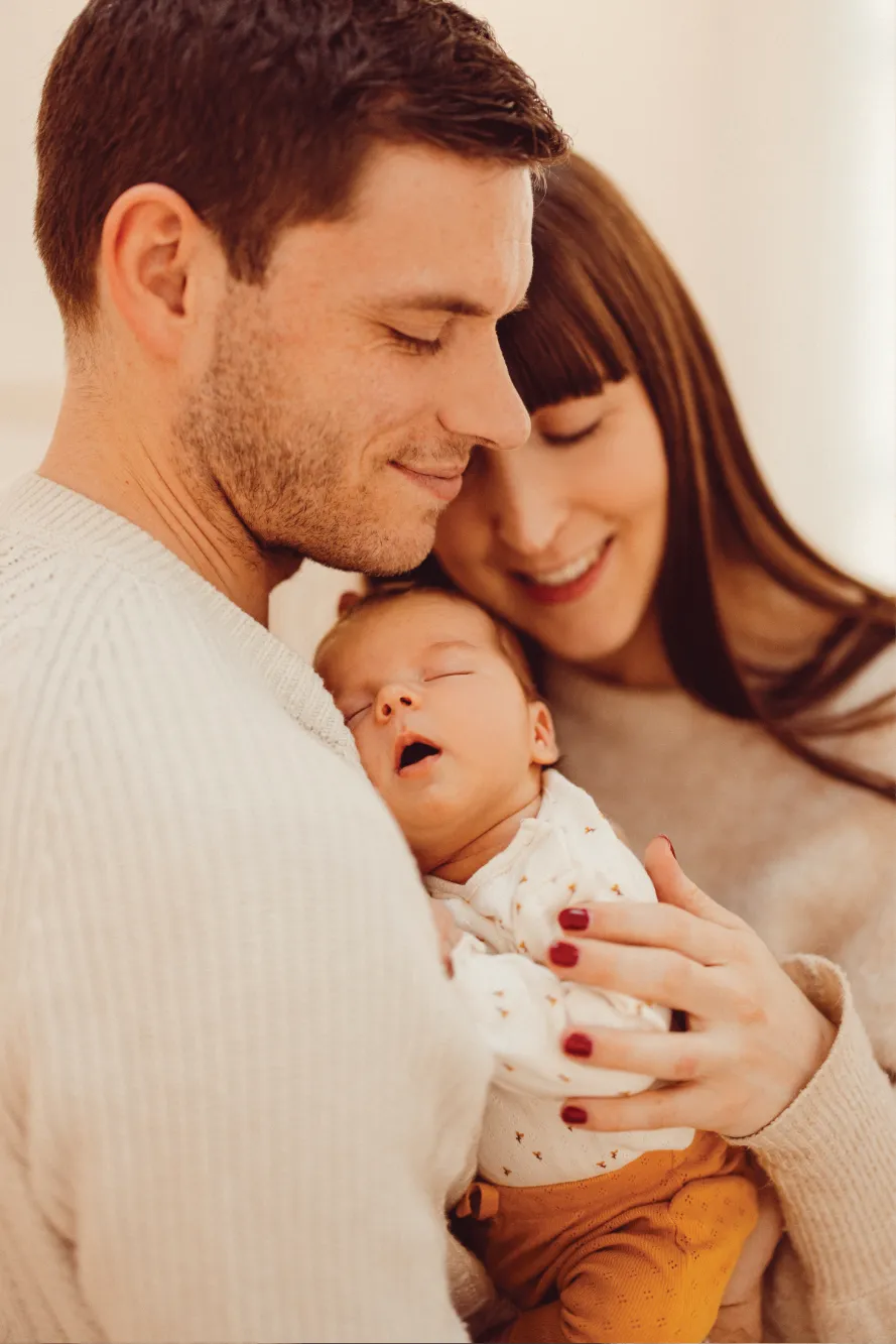 Eltern halten ihr Baby zusammen sehr eng und sind sehr fröhlich