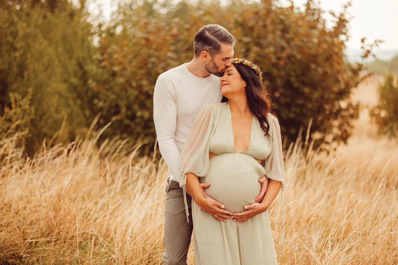 Ein Päärchen in der Natur. Mann und Frau halten den Babybauch